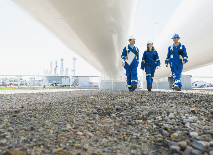 Workers walking below tanks at gas plant